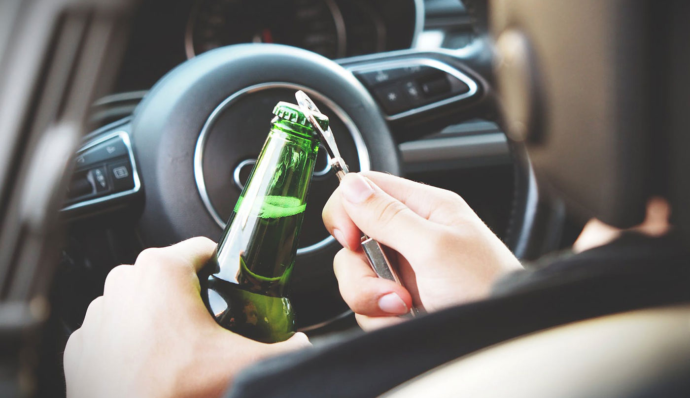 An individual opening a beer in a car, making a very difficult case for DUI defense attorneys in Peoria IL